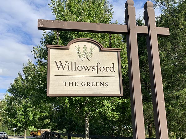 a sign for willowwood the greens on a sunny day