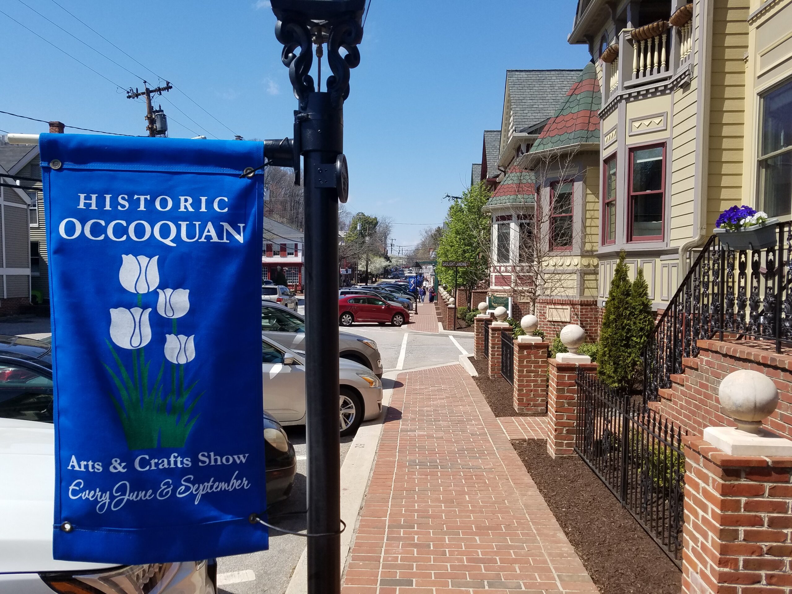 a blue banner hanging from a lamp post on a sidewalk