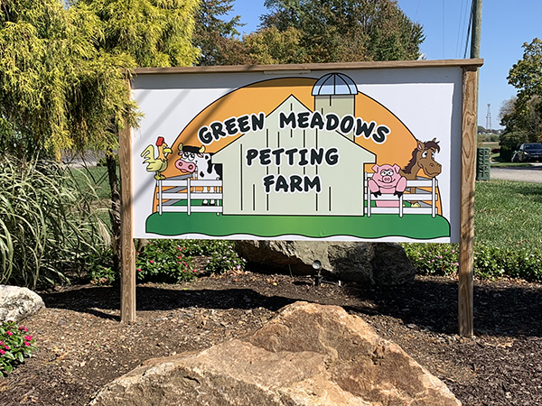 a sign for a petting farm on a sunny day