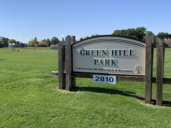 a green hill park sign in a grassy field